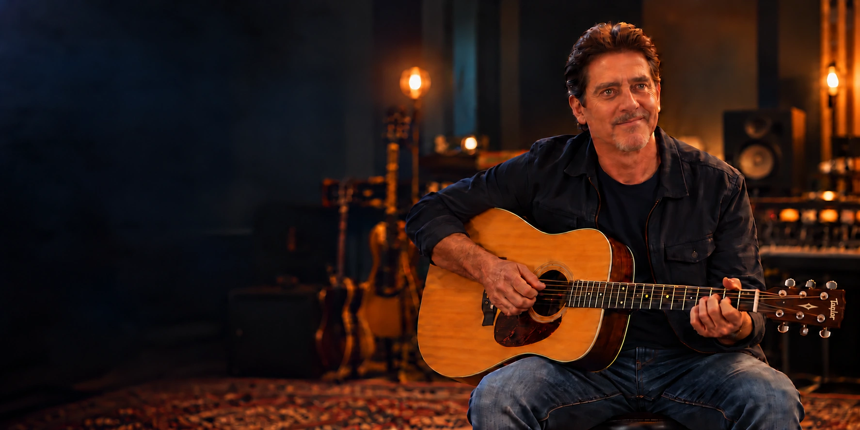 Kenny Lee Barrix seated with a Taylor acoustic guitar in a warmly lit recording studio